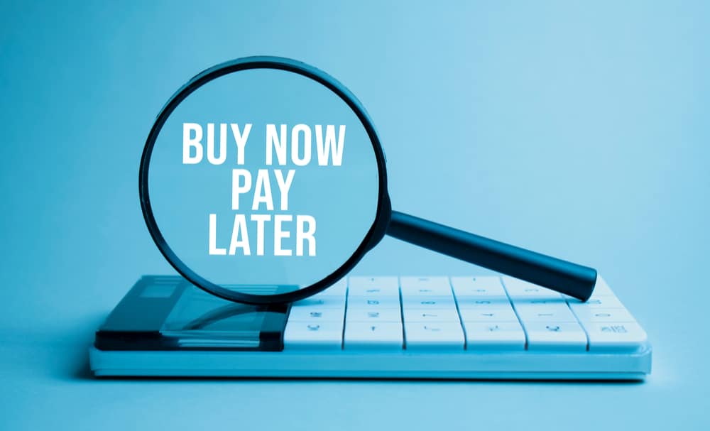 buy now pay later in a magnifying glass sitting on a calculator representing BNPL conversion rates