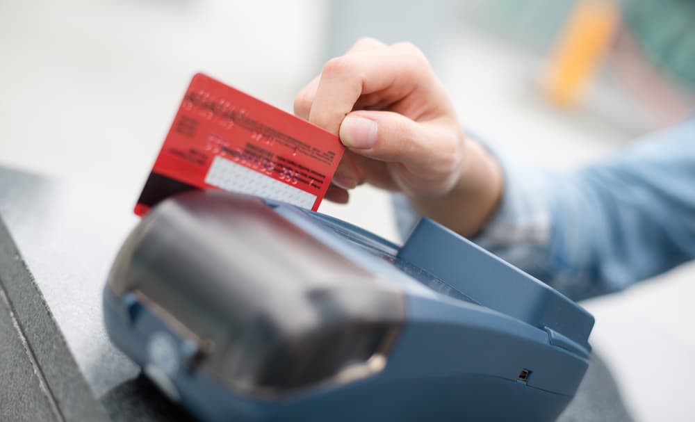  A card sliding through a point of sale which will carry merchant processing fees